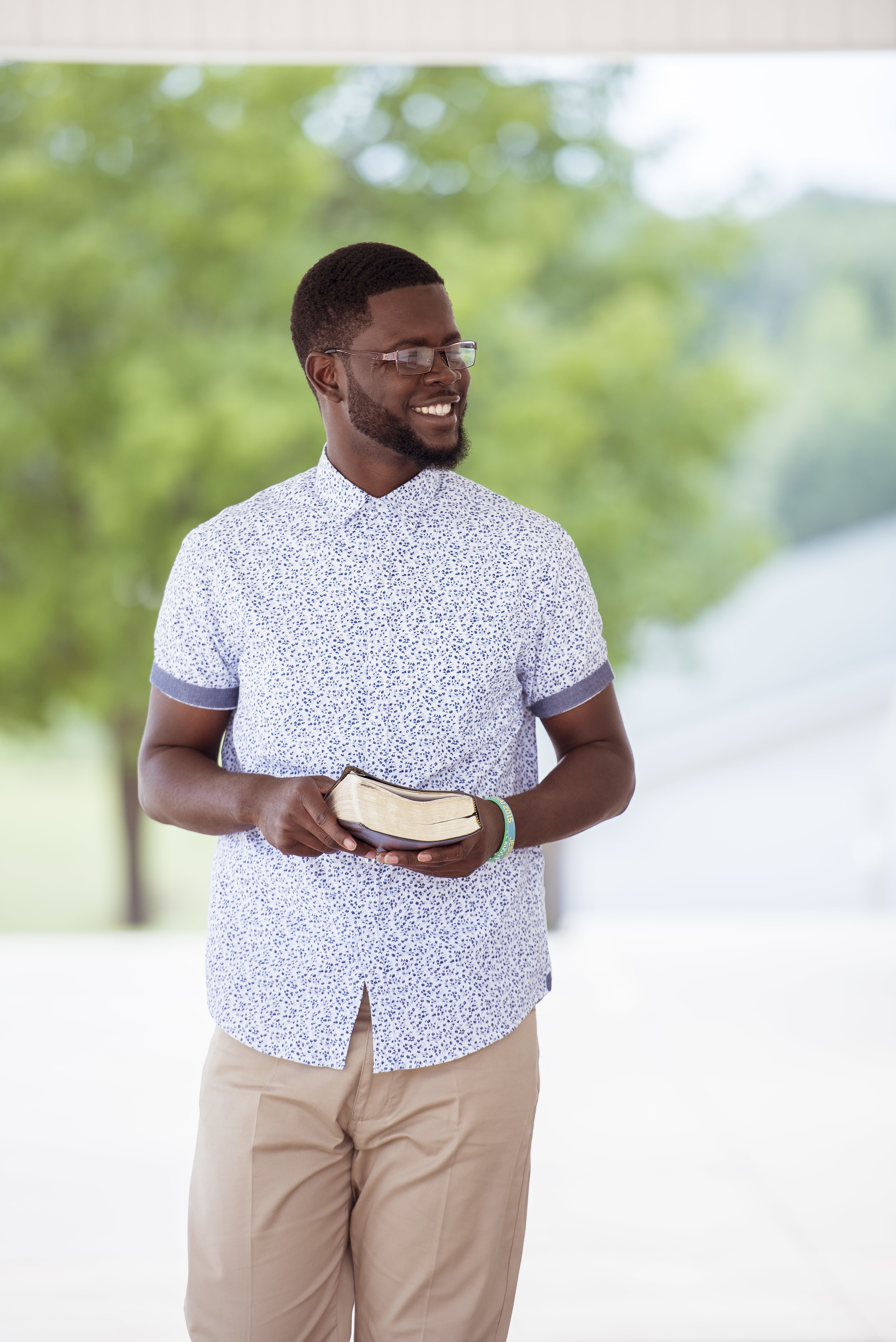 Vertical shot of a male walking while holding the bible and smiling